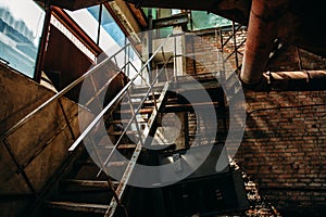 Iron rusty staircase in the brick shop of the abandoned factory, inside the interior