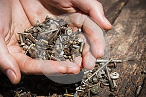 Iron rusty tools bolts and screws in his hands on an old wooden close-up selective focus