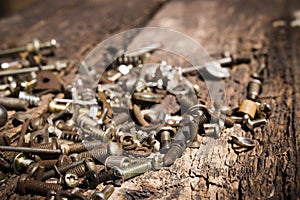 Iron rusty tools bolts and screws on an old wooden table close-up