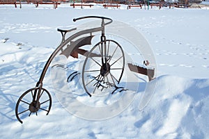 Iron sculpture of bicycle in white snow on winter time