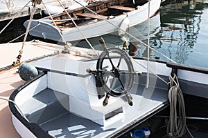 Iron steering wheel in front of boat tied to a dock