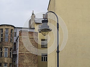Iron street lamp on industrial old cracked houses background