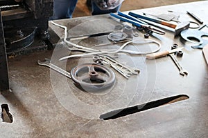 An iron table with a metalwork tool, wrenches, hammers, screwdrivers, nippers, knives, valves in the factory, a factory