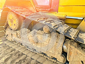 Iron track of large tractor for driving on sand and mud Detail of yellow gears, levers and valves of a tractor engine Construction