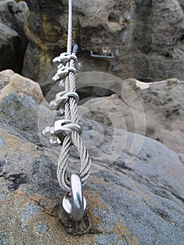 Iron twisted rope fixed in block by screws snaphooks. Detail of end of the anchored rope