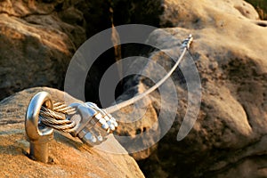 Iron twisted rope streched between rocks in climbers patch. Rope fixed in block by screws snap hooks. Detail of rope .