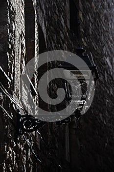 Iron vintage antique style street lantern in the stone medieval wall, spiderweb in the lantern, Spain