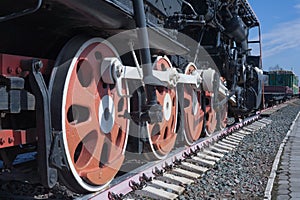 Iron wheels of mighty steam locomotives, red iron wheels of steam locomotives, steel wheels of a steam locomotive, steel power of