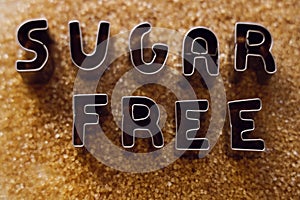 iron word - cane sugar free made from metal letters on pile of dark Brown sugar as background. no Sugar. sugarless