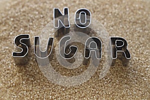 iron word - cane SUGAR free made from metal letters on pile of dark Brown sugar as background. no Sugar. sugarless