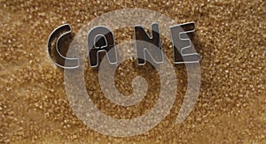 iron word - cane sugar made from metal letters on pile of dark Brown sugar.  on white table background