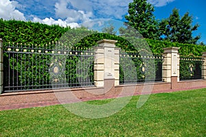 An iron wrought fence with capital stone columns.