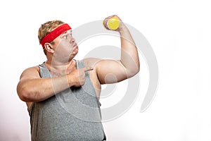 Fat funny man in red headband shows his muscles with dummbell and emotions