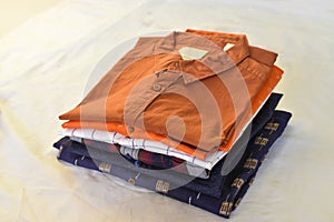 Ironing, laundry, clothes, housekeeping and objects concept - close up of ironed and folded shirts on table at home