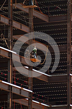 Ironworker with safety line working on the outside of steel framing against a dramatic background