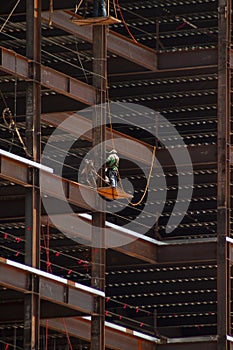 Ironworker with safety line working on the outside of steel framing against a dramatic background photo