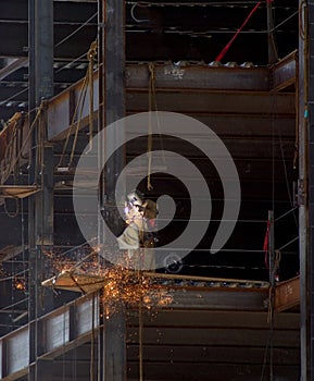 Ironworker welding on steel beams with sparks flying on a high rise