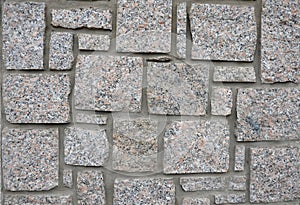 Irregular cyclopean masonry on the wall of a house or cottage. Gray granite is cut into cube shapes joined by cement.