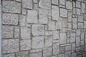 Irregular cyclopean masonry on the wall of a house or cottage. Gray granite is cut into cube shapes joined by cement.