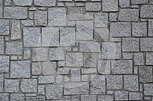 Irregular cyclopean masonry on the wall of a house or cottage. Gray granite is cut into cube shapes joined by cement.