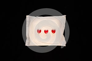 Irregular period concept. Menstrual cycle pad with red hearts on black background. Menorrhagia or heavy menstruation