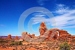 Irregular rock formations with pinnacles and arch, across a desert landscape in Utah