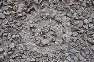 Irregular surface of gray gravel pebble dash on the wall