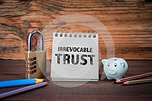 Irrevocable trust. Cardboard notepad on wooden texture table photo