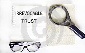 Irrevocable trust text on notepad with glasses, magnifier and notepad photo