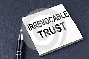 IRREVOCABLE TRUST text on the sticker with pen on the black background photo