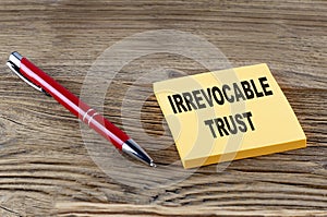 IRREVOCABLE TRUST text on sticky with pen on the wooden background photo