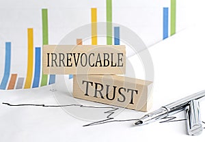 IRREVOCABLE TRUST text on a wooden block on chart background , business concept photo