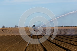 Irrigation of an agricultural field during the corona pandemic. Farmers working hard to keep the global food supply lines open