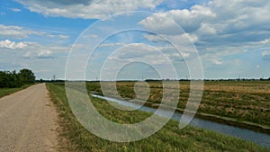 irrigation canal along a field and an empty dirt road. Reclamation channel for improving hydrological, soil and agro-climatic