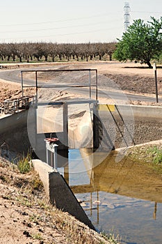 Irrigation canal gate with orchards in background