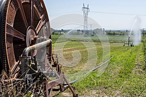 Irrigation equipment with the automatic winding mecanism in foreground spreading water over a field