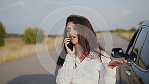 Irritated alone woman talking on phone at broken car out of city