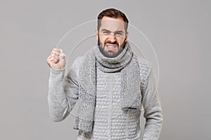 Irritated angry young man in gray sweater, scarf isolated on grey background studio portrait. Healthy lifestyle, ill