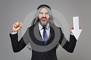 Irritated arabian muslim businessman in keffiyeh kafiya ring igal agal black suit isolated on gray background