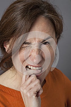 Irritated beautiful middle aged woman biting her finger, winking