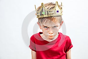 Irritated beautiful spoiled boy with dirty look and golden crown