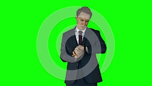 Irritated businessman checking time on green screen