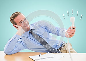 Irritated businessman holding telephone receiver at desk