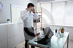 Irritated Businessman Looking At Printer Machine