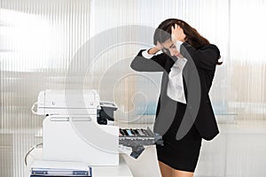 Irritated Businesswoman Looking At Printer Machine At Office