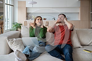 Irritated couple plugging ears disturbed by noisy neighborhood, unpleasant nervous sounds, booming