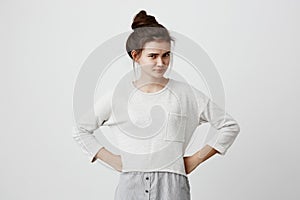 Irritated and dissatisfied brunette girl with hairbun and oval face, dark eyes, wearing loose casual sweater, frowning