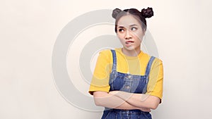 Irritated and dissatisfied girl with hairbun and oval face standing with arms akimbo, being displeased