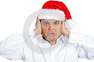 Irritated handsome man in red xmas hat shutting off his ears