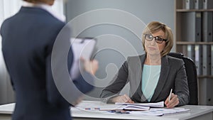 Irritated lady manager deciding what to do with office trainee, poor performance